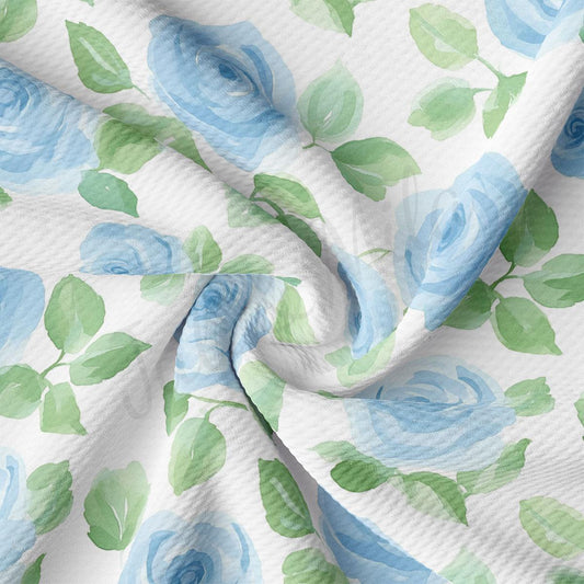a close-up view of a fabric with a floral pattern of blue roses and green leaves. The fabric appears to be wrinkled, giving it a soft and delicate appearance.
