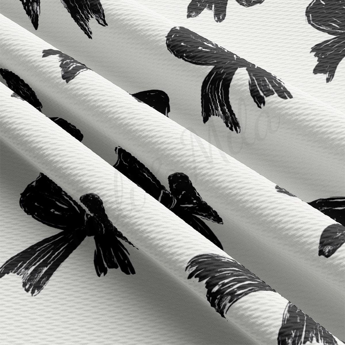 a close-up view of a fabric with a repeating pattern of black and white bows.