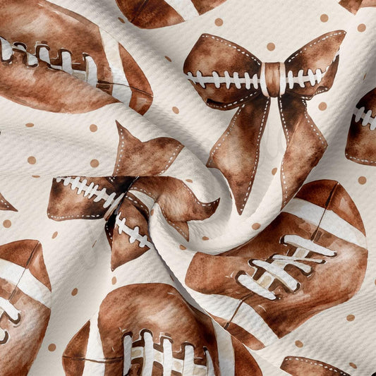 a close-up view of a fabric with a repeating pattern of brown footballs and brown bows.