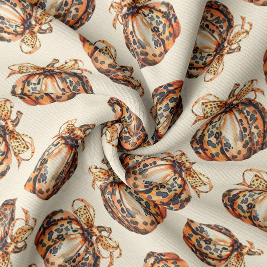 a close-up view of a fabric with a repeating pattern of orange and black spotted pumpkins.