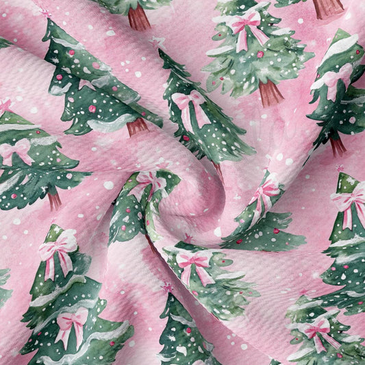 a close-up view of a fabric with a repeating pattern of Christmas trees and pink bows.