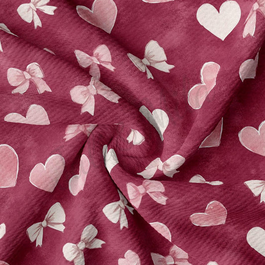 a close-up view of a fabric with a repeating pattern of pink hearts and white bows.