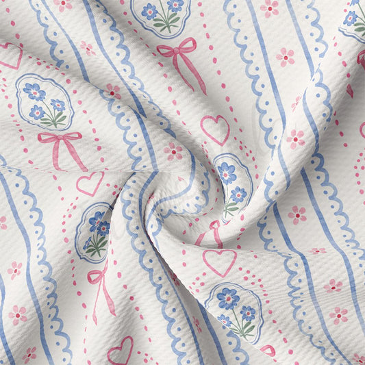 The image is a close-up of a fabric with a floral pattern, featuring blue and pink flowers, hearts, and bows.