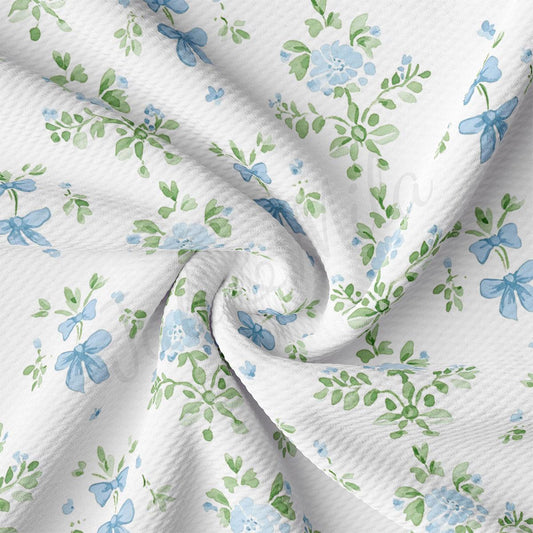 a close-up view of a fabric with a floral pattern in shades of blue and green. The fabric appears to be made of a soft, white material and has a crinkled texture.