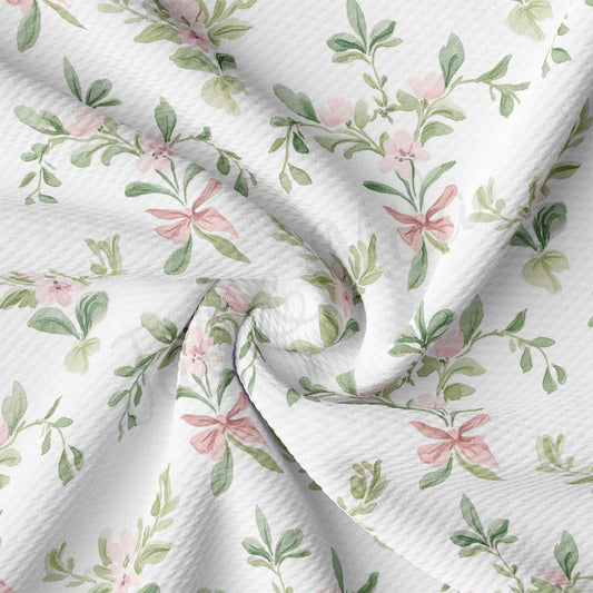 a close-up view of a fabric with a floral pattern. The fabric appears to be white and features a repeating pattern of pink flowers and green leaves. The pattern is intricate and detailed, creating a visually appealing design.