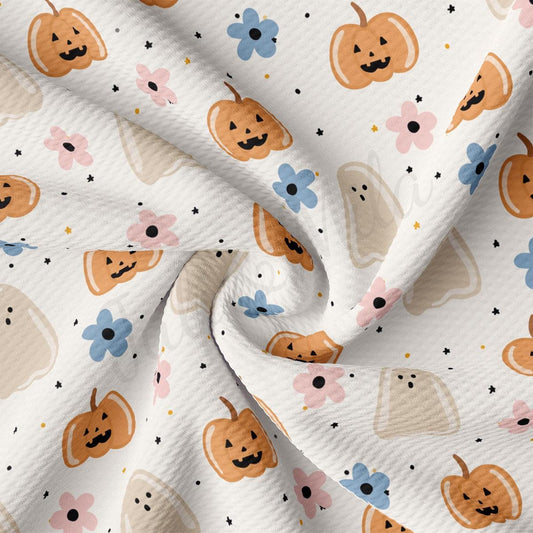 a close-up view of a fabric with a repeating pattern of Halloween-themed pumpkins and flowers.