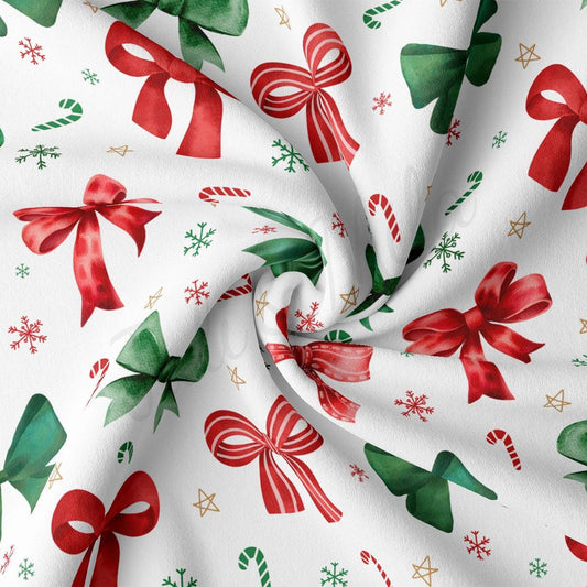 a white fabric with a repeating pattern of red and green bows, snowflakes, and candy canes.