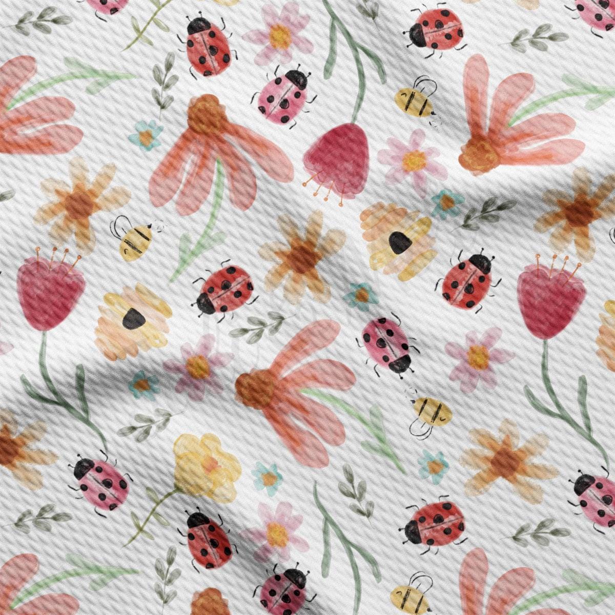 a close up of a white fabric with flowers and ladybugs on it