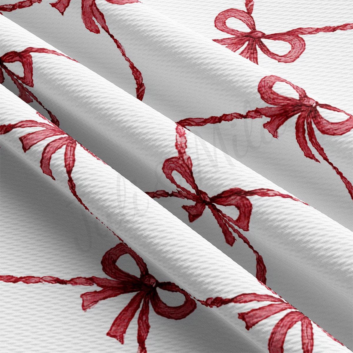 a close-up view of a fabric with a repeating pattern of red bows on a white background.