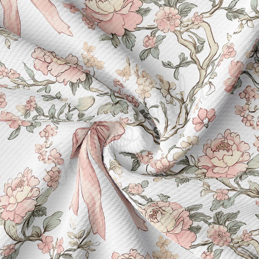 a close-up view of a fabric with a floral pattern, including pink and white flowers, leaves, and branches. The fabric appears to be made of a soft, textured material, possibly cotton or linen. The pattern is intricate and detailed, with the flowers and leaves arranged in a way that creates a visually appealing and harmonious design.