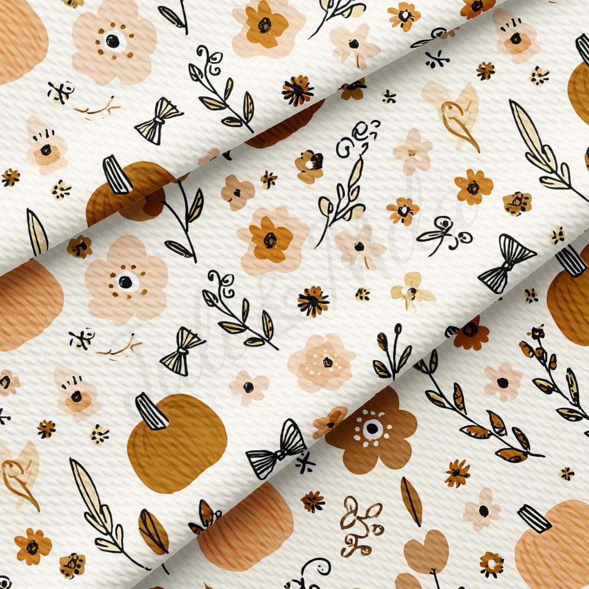 The image is a close-up of a fabric with a repeating pattern of autumn-themed elements, including pumpkins, leaves, flowers, and other fall-inspired designs.