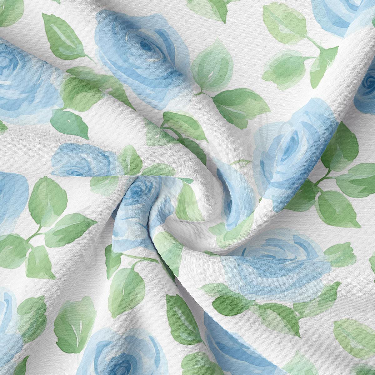 a close-up view of a fabric with a floral pattern of blue roses and green leaves. The fabric appears to be wrinkled, giving it a soft and delicate appearance.