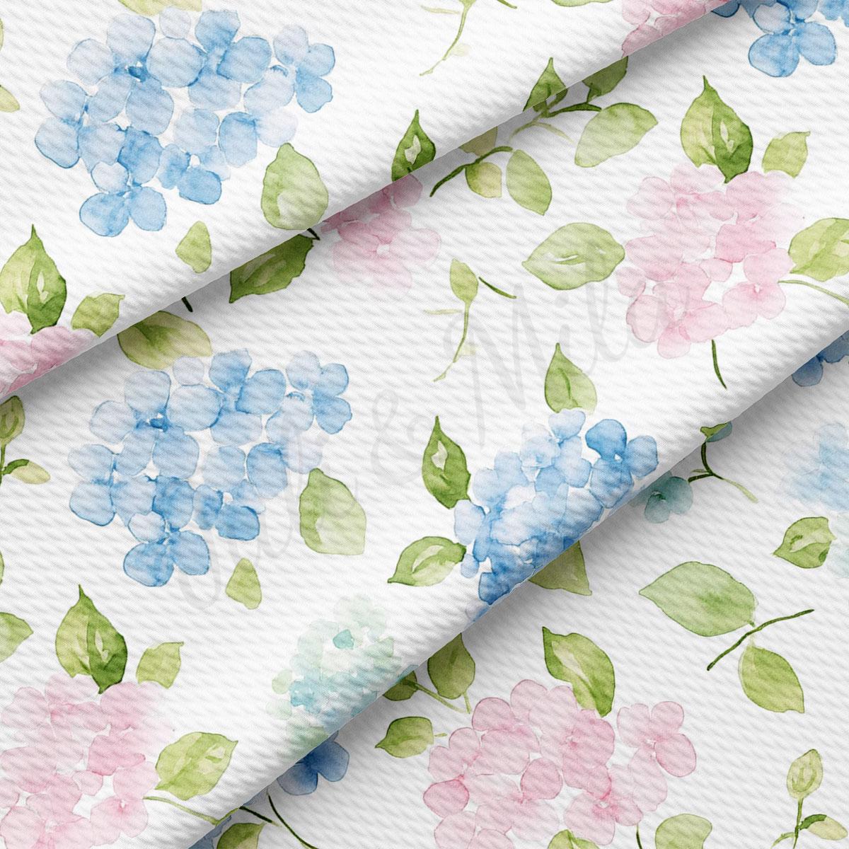 a close-up view of a fabric with a floral pattern. The pattern consists of blue hydrangea flowers and green leaves, creating a visually appealing and vibrant design.