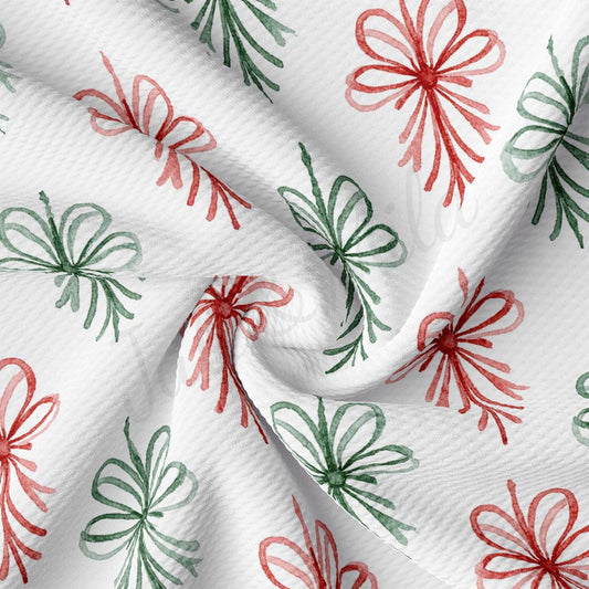 a close-up view of a fabric with a repeating pattern of red and green bows on a white background.