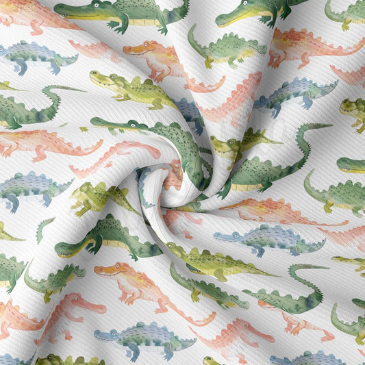 a close up of a white fabric with green and orange dinosaurs on it