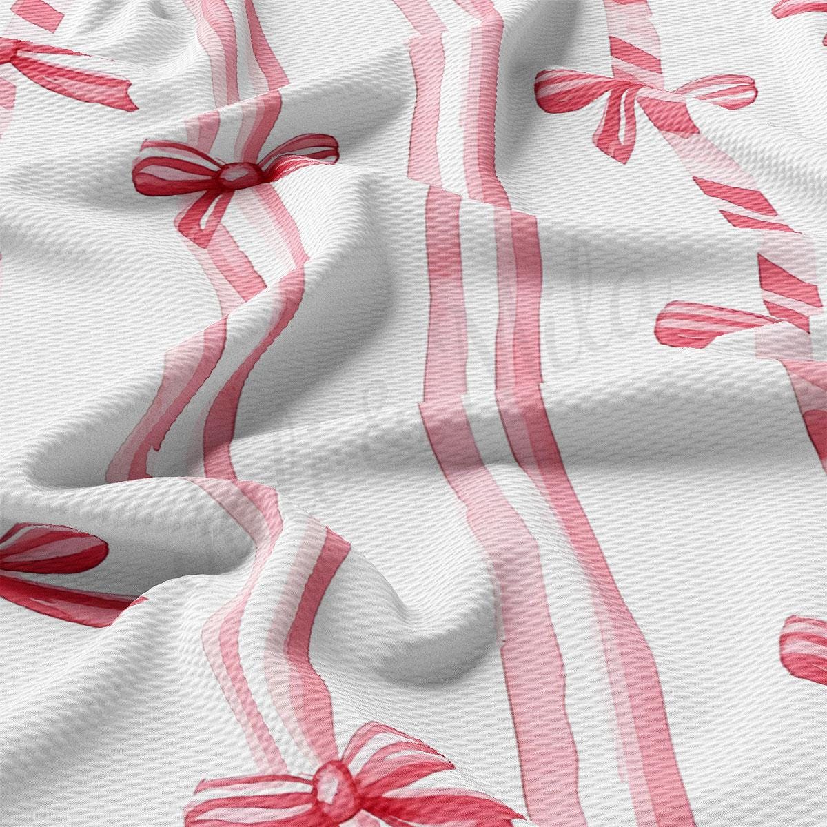 The image is a close-up of a fabric with a repeating pattern of red and white ribbons and bows.