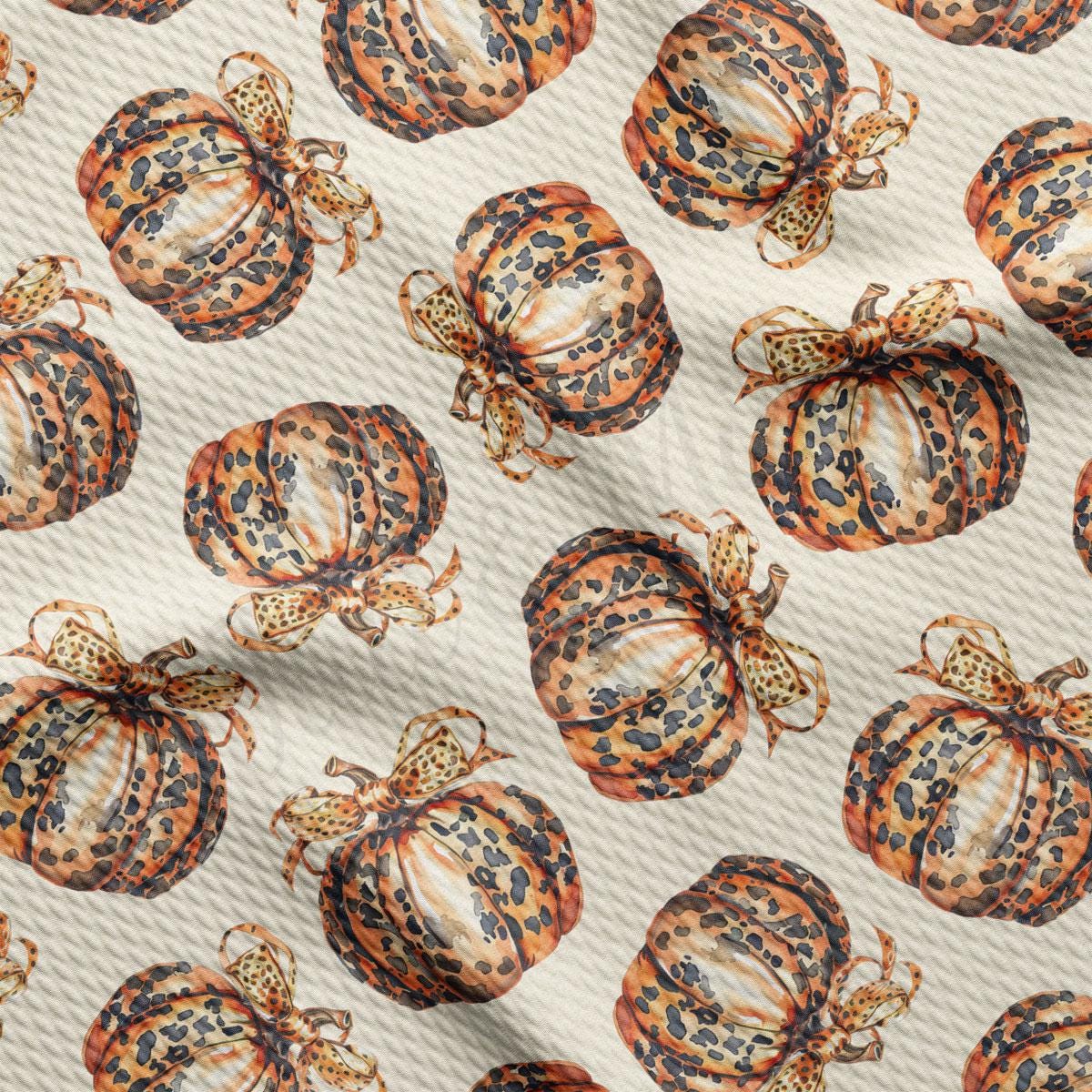 a repeating pattern of leopard print pumpkins with bows on a white background.