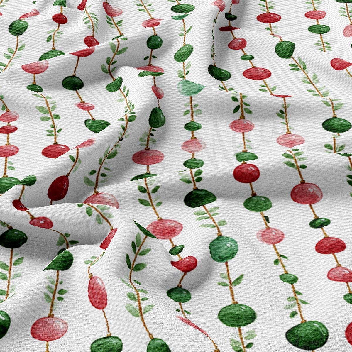 a close-up view of a fabric with a repeating pattern of red and green beads or balls, along with green leaves or branches. The pattern is arranged in a diagonal line across the fabric, creating a visually striking and textured appearance.
