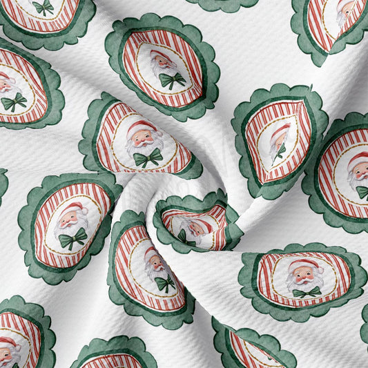 The image is a close-up of a fabric with a repeating pattern of Santa Claus faces and green scalloped edges.