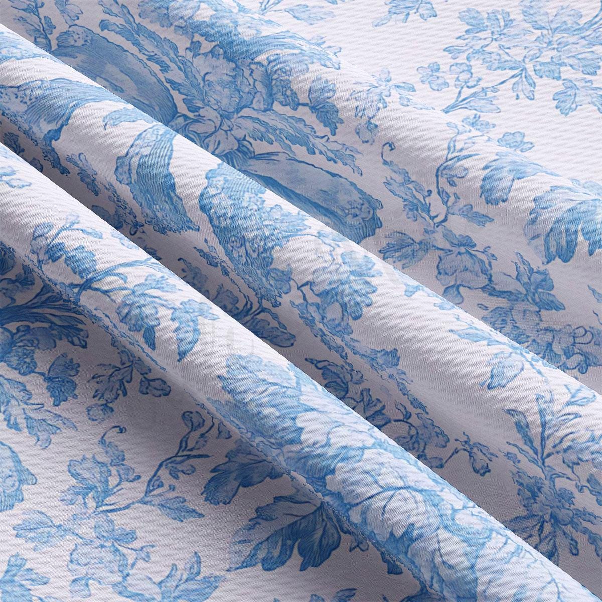 a close-up view of a fabric with a blue floral pattern. The fabric appears to be folded or rolled, revealing the intricate design of the blue flowers and leaves.