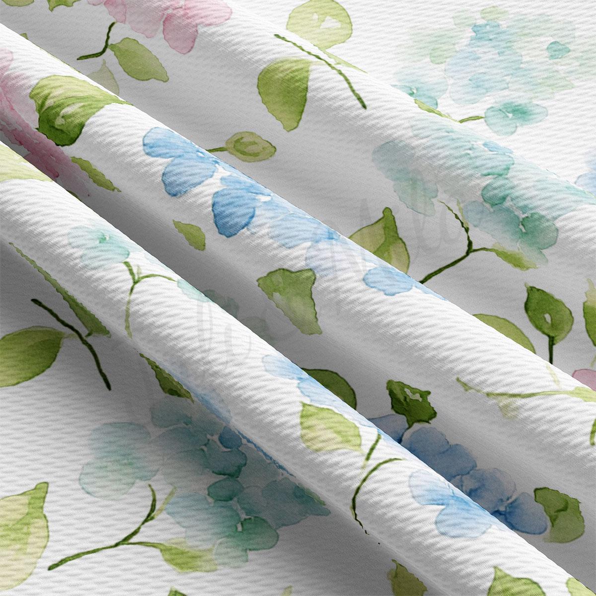 a close-up view of a fabric with a floral pattern, including green and blue flowers and leaves. The fabric appears to be white, and the pattern is intricate and detailed.