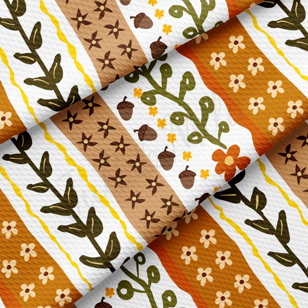 The image is a close-up of a fabric with a repeating pattern of leaves, flowers, and acorns in various shades of brown, orange, and yellow.