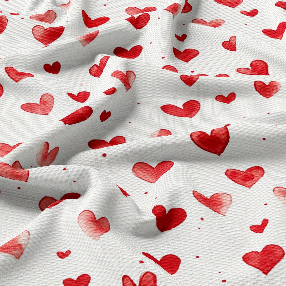 a close-up view of a fabric with a repeating pattern of red hearts on a white background.