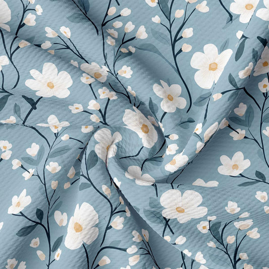 a close-up view of a fabric with a floral pattern. The fabric has a blue background with white flowers and leaves, creating a visually appealing and delicate design.