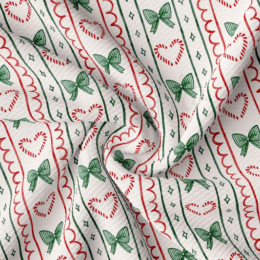 The image is a close-up view of a fabric with a repeating pattern of green and red bows, candy canes, and hearts. The pattern is arranged in a zigzag or wavy design, creating a festive and decorative appearance.