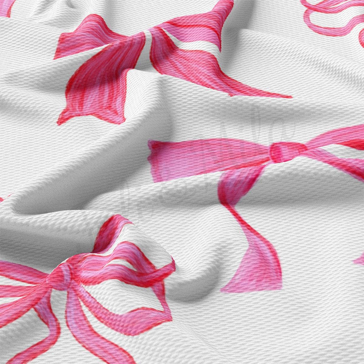 a close up of a white fabric with pink bows