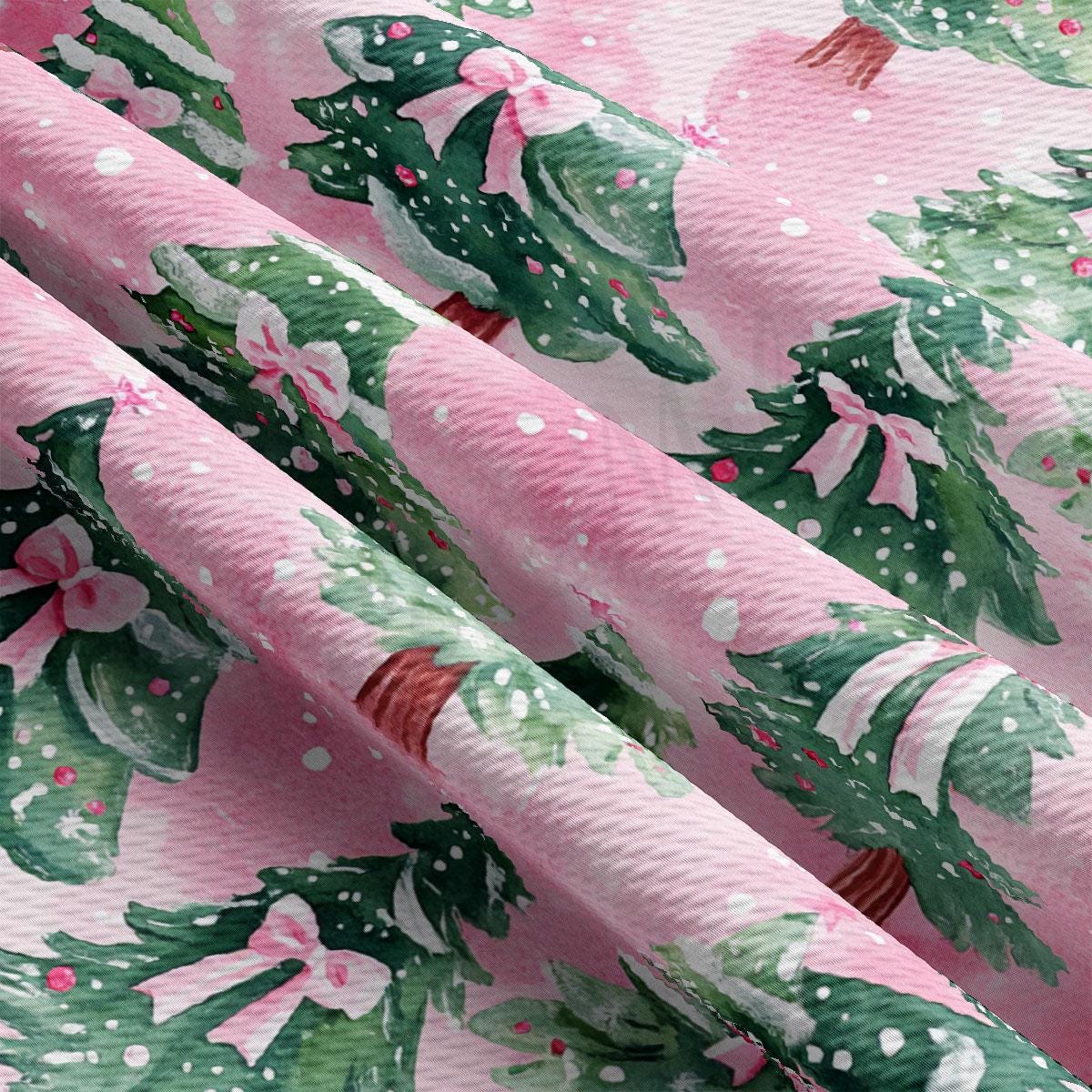 a close-up view of a fabric with a repeating pattern of green Christmas trees and pink bows.