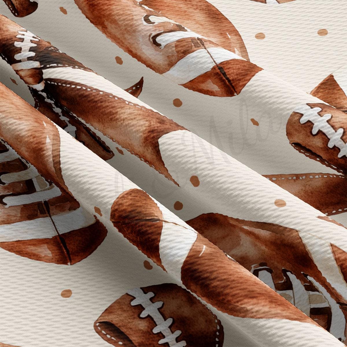 a close-up view of a fabric with a repeating pattern of brown footballs and white stitching.