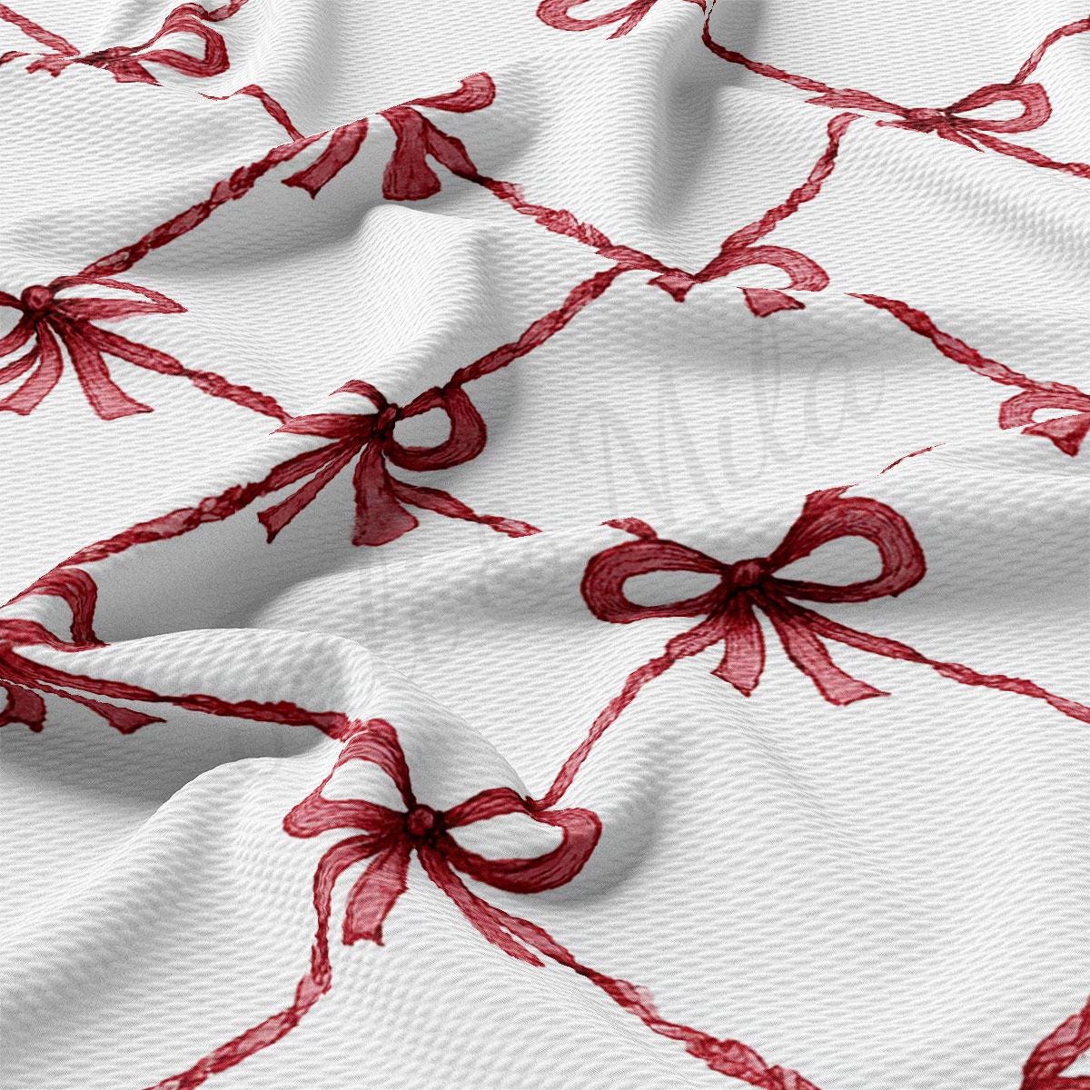 a close-up view of a fabric with a repeating pattern of red bows on a white background.