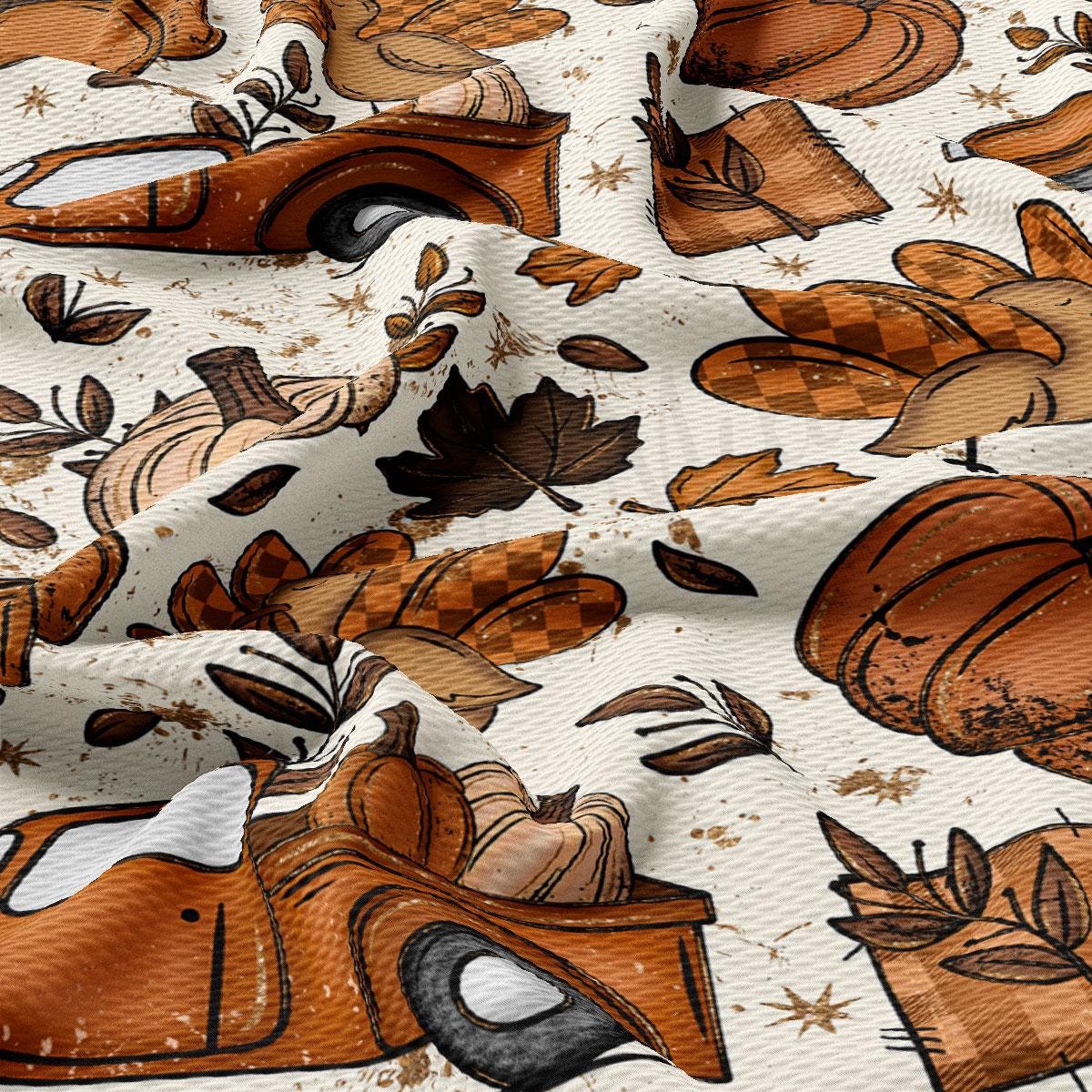 The image is a close-up of a fabric with a repeating pattern of autumn-themed illustrations, including pumpkins, leaves, and other seasonal elements. The pattern is predominantly brown and orange, with some black and white accents. The fabric appears to be wrinkled, giving it a textured and rustic appearance.