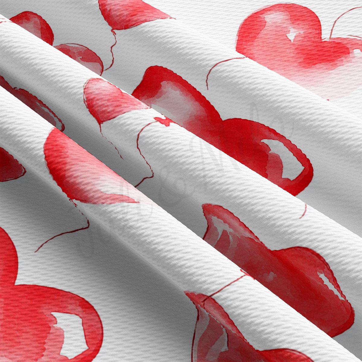 a close-up view of a fabric with a repeating pattern of red heart shapes.