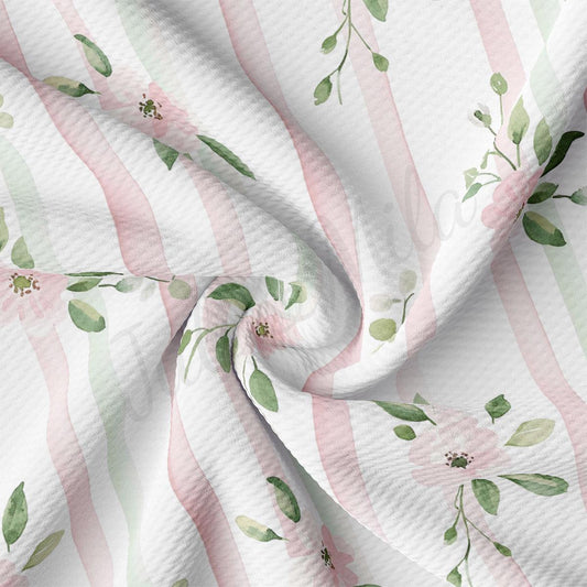 a close-up view of a fabric with a floral pattern of pink and green stripes and leaves.