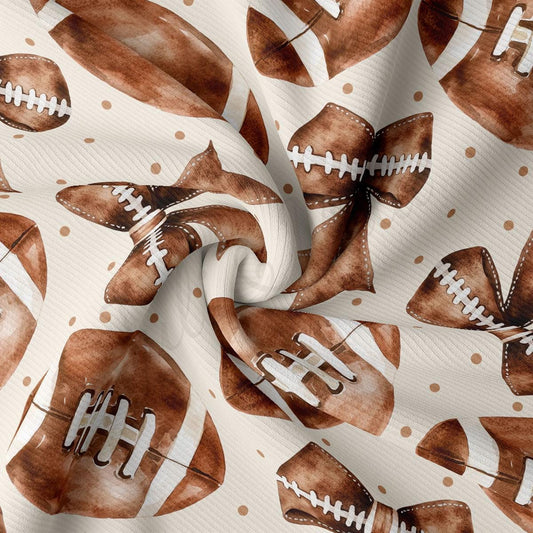 a close-up view of a fabric with a repeating pattern of brown footballs and white stitching.