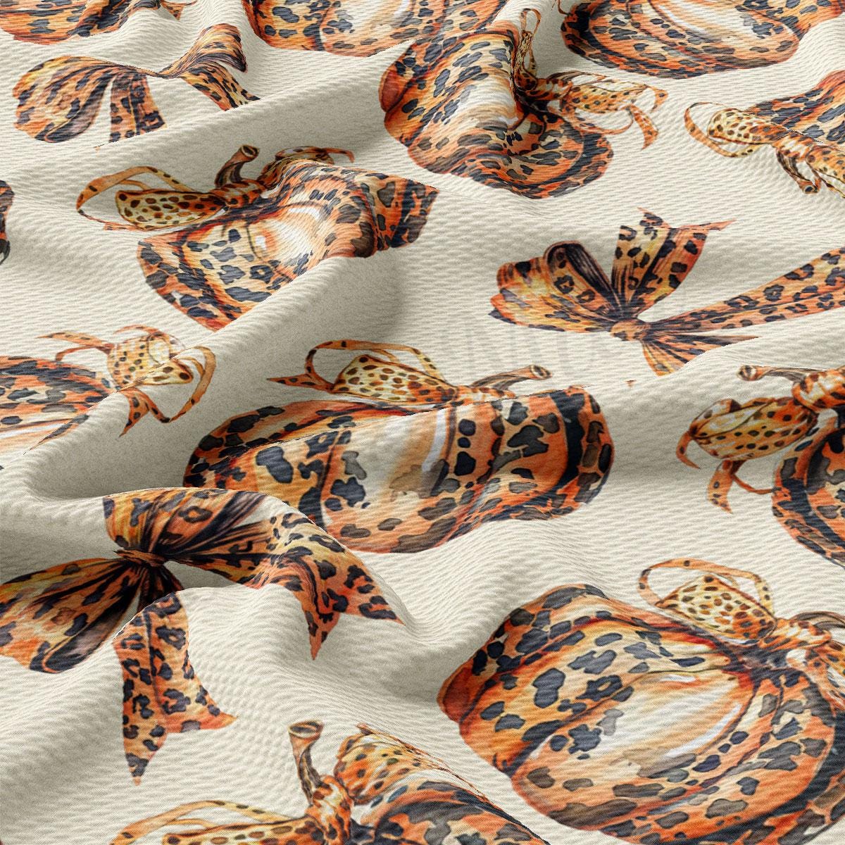 a close-up view of a fabric with a repeating pattern of leopard-print designs, including animals like butterflies and birds. The pattern is predominantly orange and black, creating a visually striking and vibrant design.