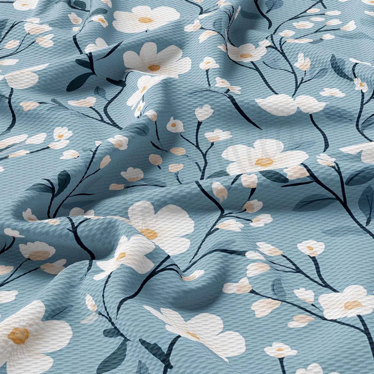 a close-up view of a fabric with a floral pattern. The fabric has a blue background with white flowers and green leaves, creating a visually appealing and textured design.