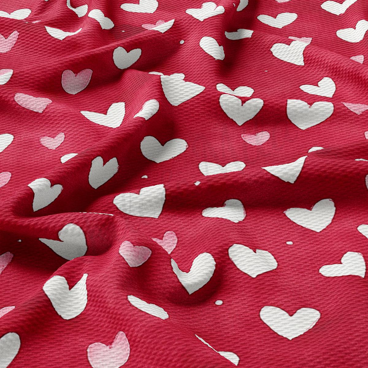 a close-up view of a red fabric with white hearts printed on it. The hearts are scattered across the fabric in a random pattern, creating a visually interesting and textured appearance.