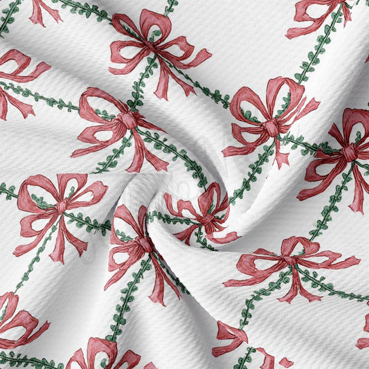 a close-up view of a fabric with a repeating pattern of red bows and green leaves. The bows are arranged in a diagonal pattern, creating a sense of movement and dynamism across the fabric. The green leaves add a touch of natural texture and color to the overall design.