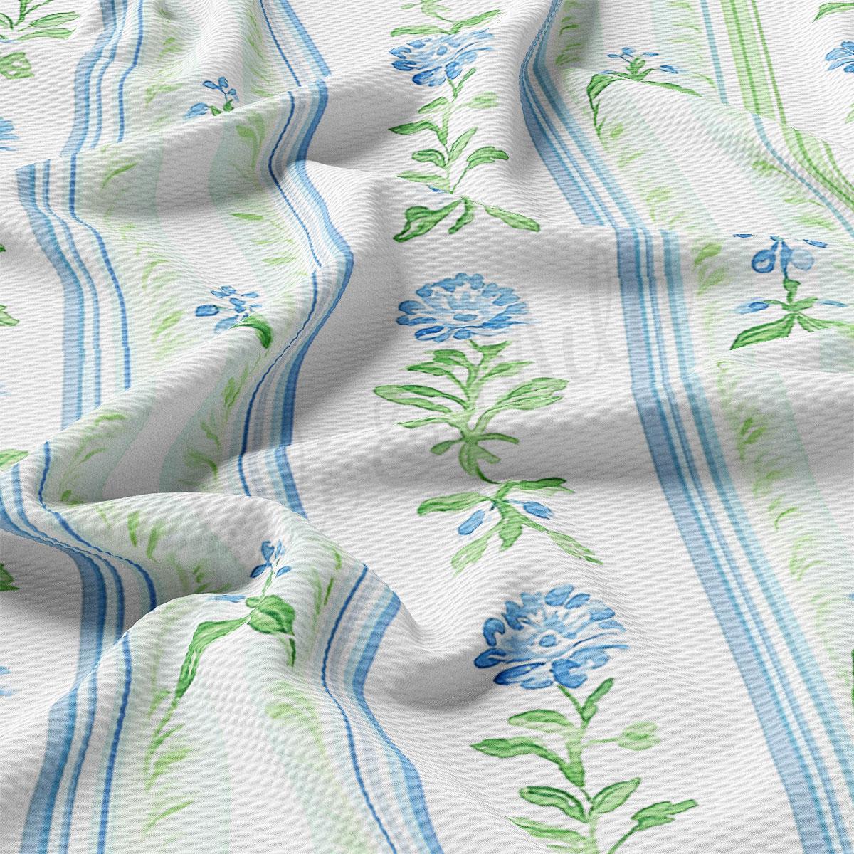 a close-up view of a fabric with a floral pattern in shades of blue and green. The fabric appears to be crumpled and wrinkled, giving it a textured and soft appearance.