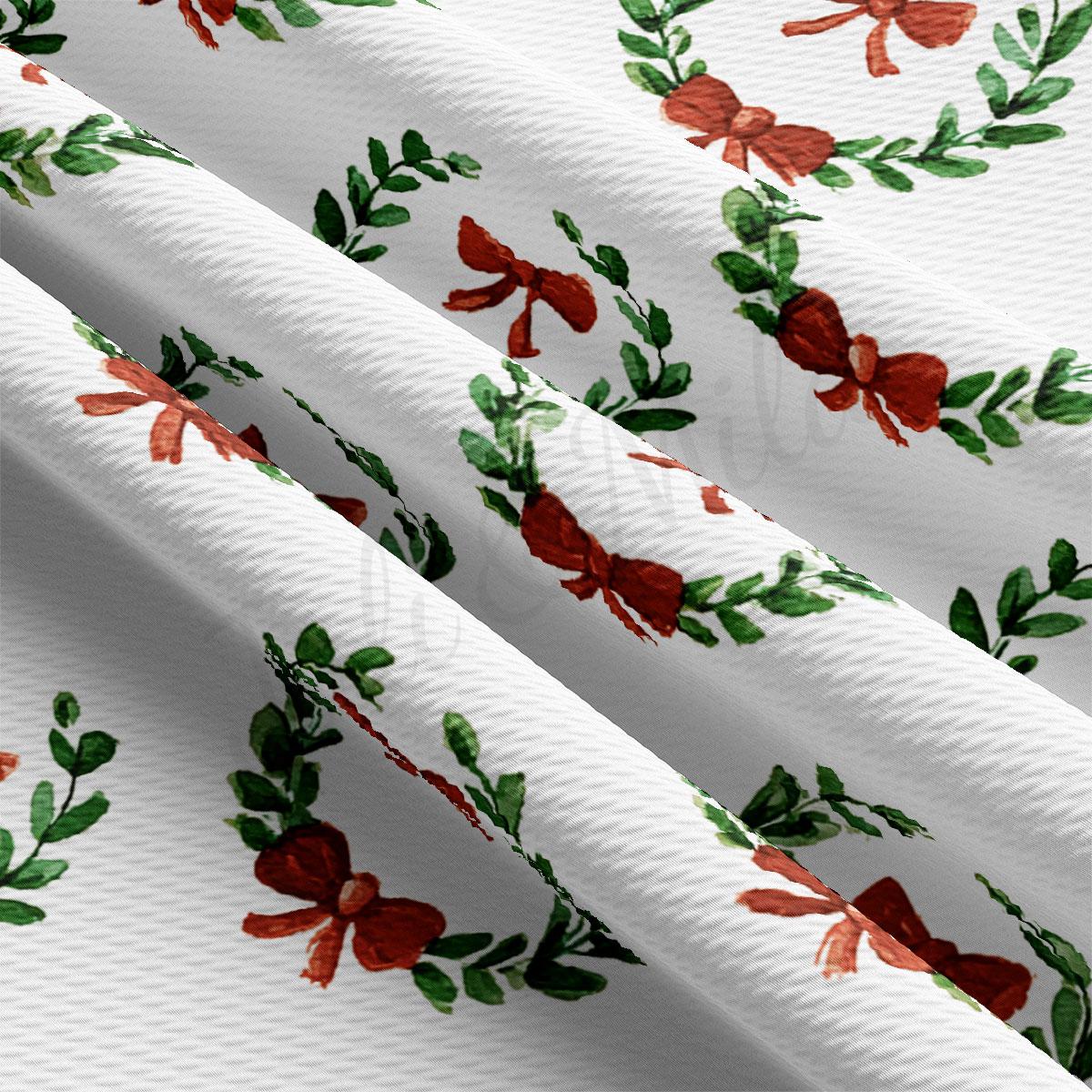 a close-up view of a fabric with a repeating pattern of red bows and green leaves.