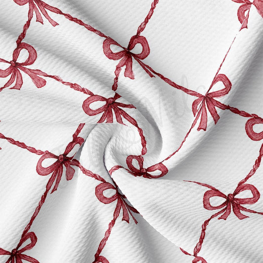 a close-up view of a fabric with a repeating pattern of red bows on a white background.