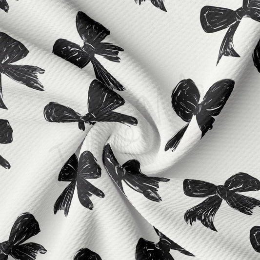 a close-up view of a fabric with a repeating pattern of black bows on a white background.