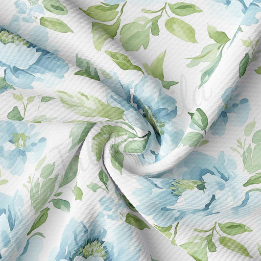 a close-up view of a fabric with a floral pattern in shades of blue and green. The fabric appears to be crumpled and wrinkled, giving it a textured and organic appearance.