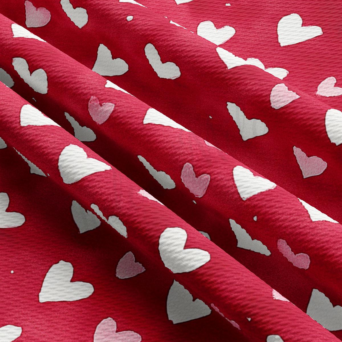 a close-up view of a red fabric with white hearts printed on it. The fabric appears to be folded or crumpled, creating a textured and layered appearance.