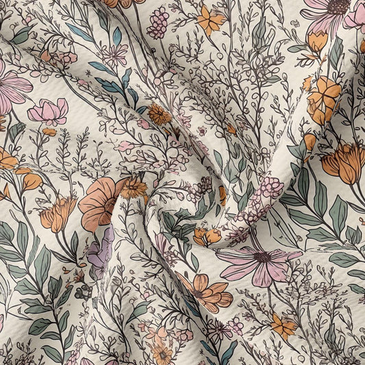 The image is a close-up view of a fabric with a floral pattern. The fabric has a variety of flowers and leaves in different colors, including pink, orange, and green. The pattern is intricate and detailed, with the flowers and leaves overlapping and intermingling. The fabric appears to be made of a soft, textured material, suitable for clothing or home decor.