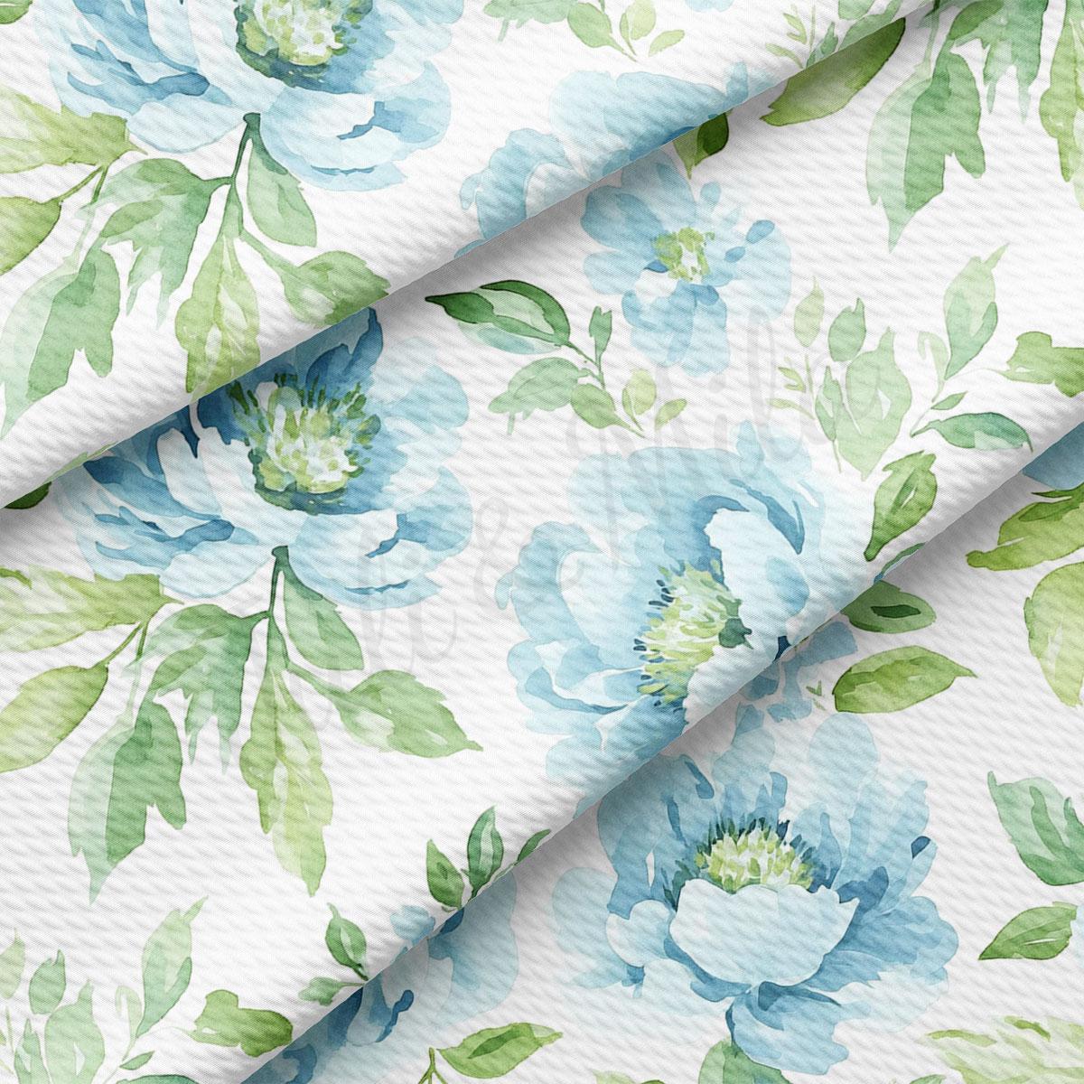 a close-up view of a fabric with a floral pattern. The pattern consists of blue flowers with green leaves, creating a visually appealing and harmonious design.
