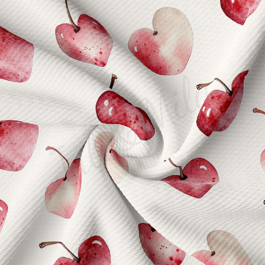 a close-up view of a white fabric with a repeating pattern of red heart-shaped apples.
